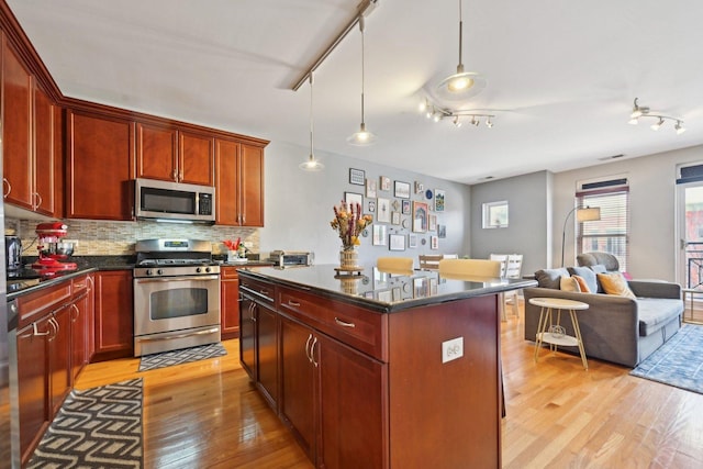 kitchen featuring a center island, stainless steel appliances, dark countertops, hanging light fixtures, and open floor plan