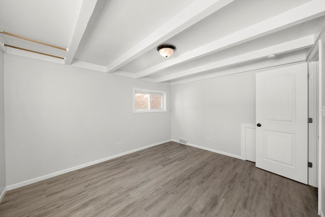 unfurnished room with visible vents, baseboards, beamed ceiling, and wood finished floors