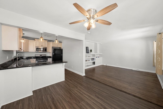 kitchen featuring dark countertops, appliances with stainless steel finishes, a peninsula, hanging light fixtures, and a sink