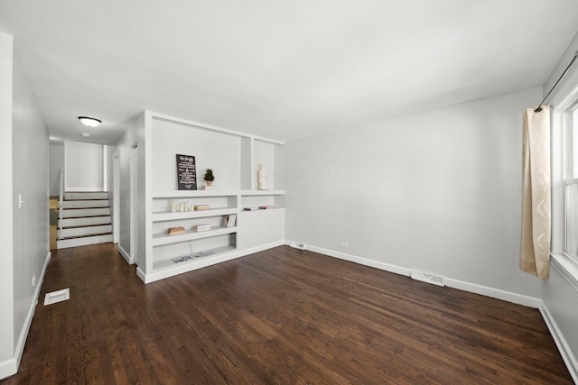 spare room featuring dark wood-type flooring, visible vents, stairway, and baseboards