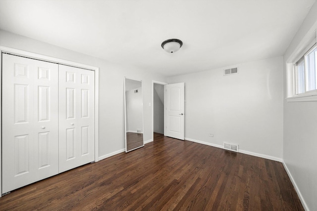 unfurnished bedroom featuring baseboards, visible vents, and dark wood-style flooring