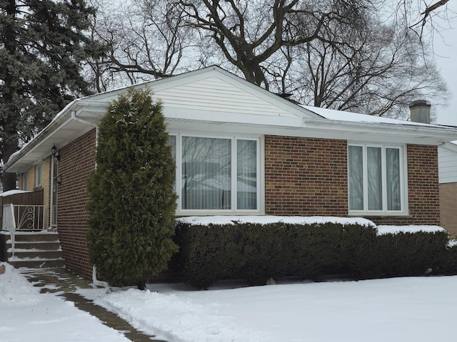 snow covered property featuring brick siding