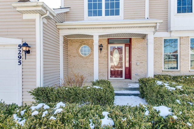 entrance to property with a garage and brick siding