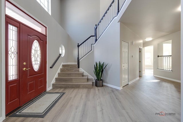 entryway featuring stairway, light wood-style flooring, and baseboards