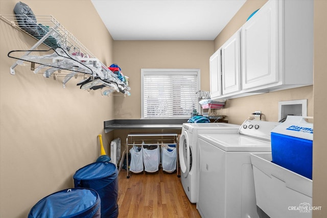 laundry room with washer and dryer, cabinet space, and light wood-style floors