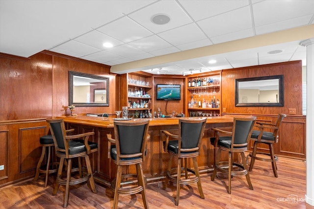 bar featuring wooden walls, wood finished floors, and a community bar