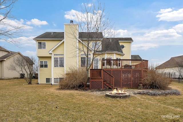 rear view of property featuring a fire pit, a wooden deck, stairs, a lawn, and a chimney