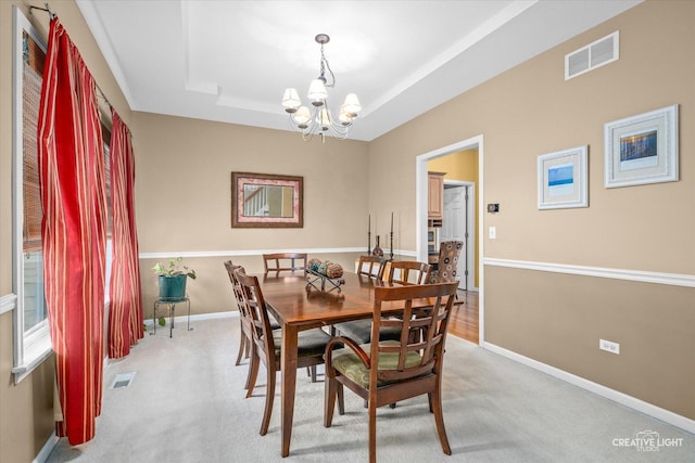 dining room featuring visible vents, a raised ceiling, light colored carpet, and a notable chandelier