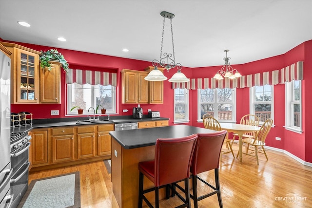 kitchen featuring dark countertops, appliances with stainless steel finishes, light wood-style floors, plenty of natural light, and a sink