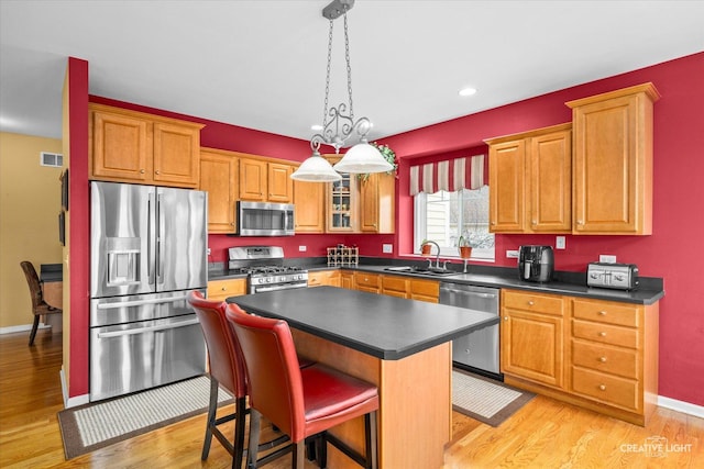 kitchen with dark countertops, visible vents, light wood-type flooring, stainless steel appliances, and a sink