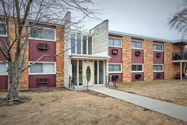 view of front of property featuring a wall unit AC and a front yard