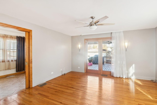 spare room featuring baseboards, ceiling fan, visible vents, and wood finished floors