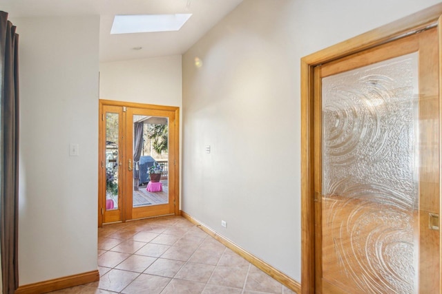 entryway with lofted ceiling with skylight, baseboards, and light tile patterned floors