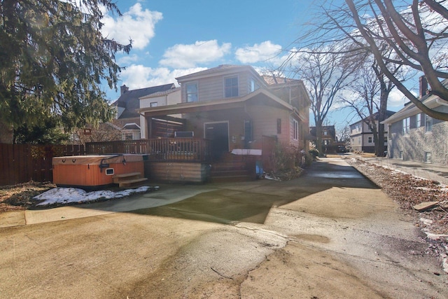 view of front of property with a hot tub and fence