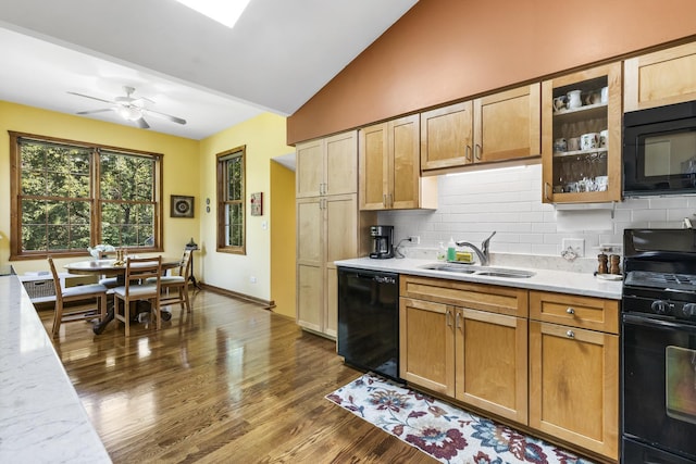 kitchen featuring tasteful backsplash, dark wood-type flooring, vaulted ceiling, a sink, and black appliances