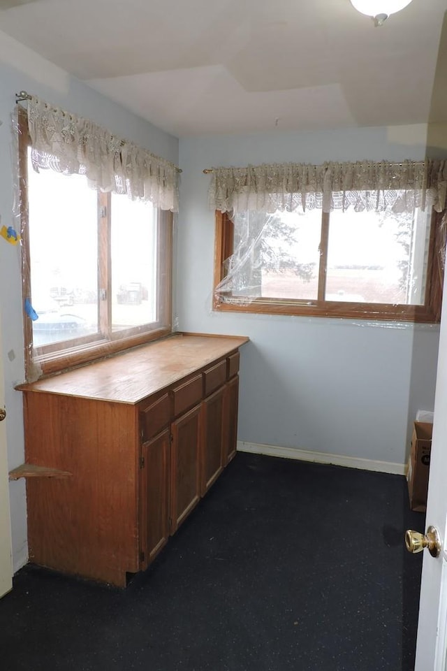 kitchen featuring dark carpet, brown cabinets, and baseboards