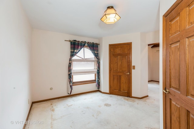 spare room with light colored carpet and baseboards