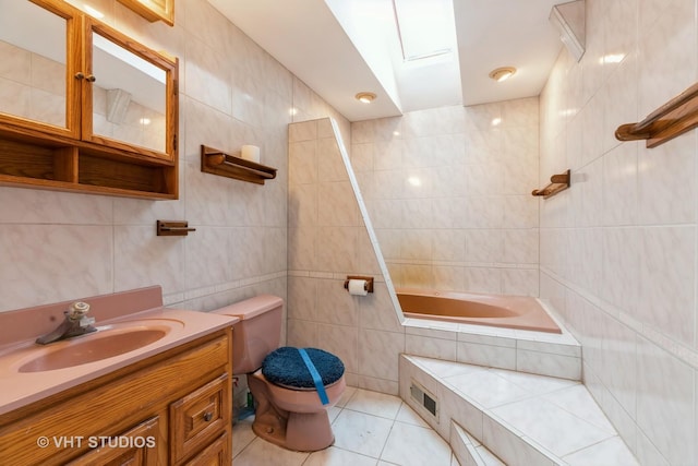 bathroom with toilet, tiled shower / bath combo, vanity, tile walls, and tile patterned floors