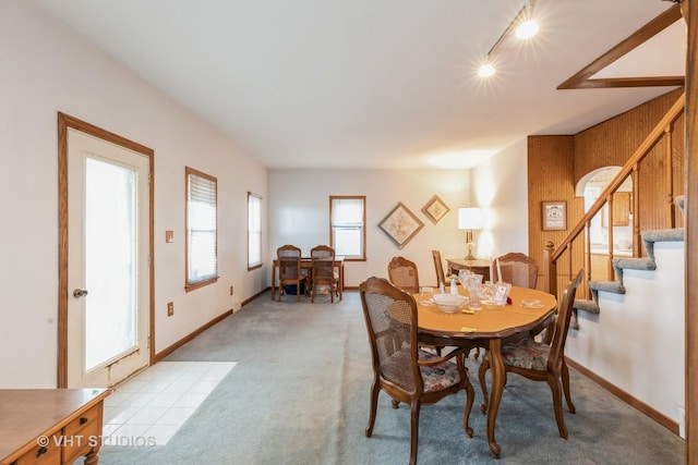 dining room featuring light carpet, stairs, and baseboards