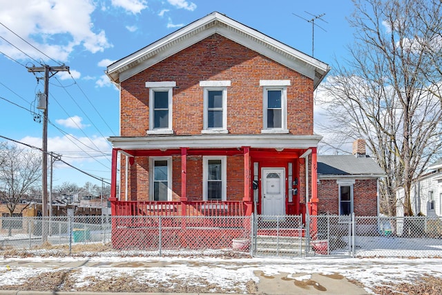 view of front of property with brick siding, a porch, and a fenced front yard