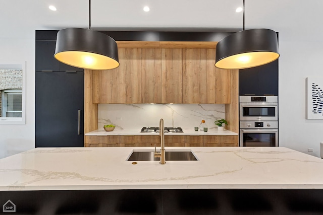 kitchen featuring appliances with stainless steel finishes, tasteful backsplash, light stone counters, decorative light fixtures, and sink