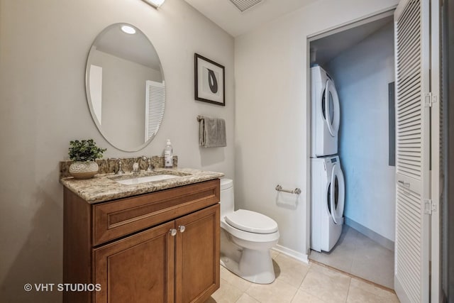 half bathroom featuring visible vents, stacked washer and clothes dryer, toilet, tile patterned floors, and vanity