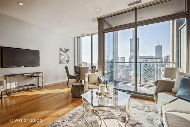 living area with a view of city, recessed lighting, visible vents, light wood-style flooring, and baseboards