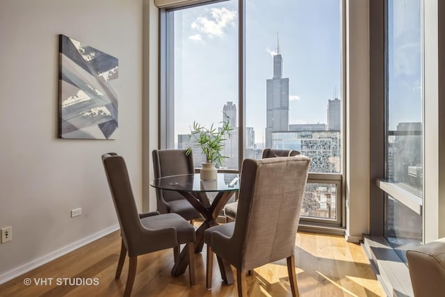 dining space featuring a view of city, light wood-type flooring, and baseboards