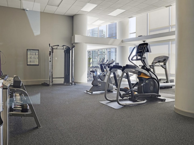 gym with a high ceiling, baseboards, and a drop ceiling