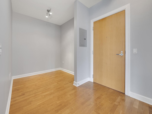 empty room with light wood-style floors, electric panel, and baseboards