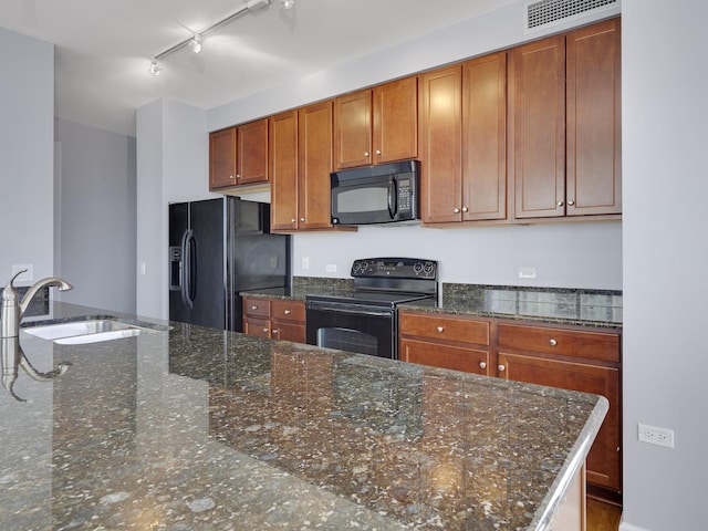 kitchen featuring brown cabinetry, visible vents, a sink, and black appliances