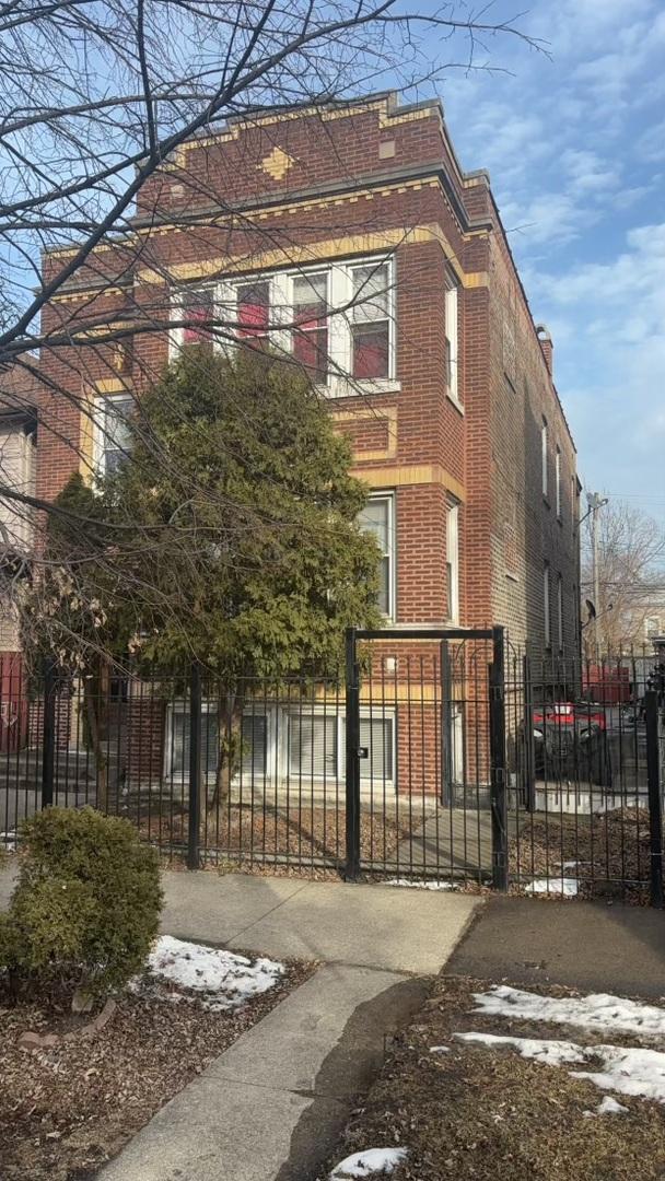 view of front of property with brick siding, a fenced front yard, and a gate