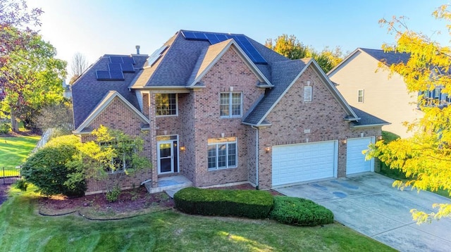 traditional-style house featuring brick siding, solar panels, an attached garage, driveway, and a front lawn