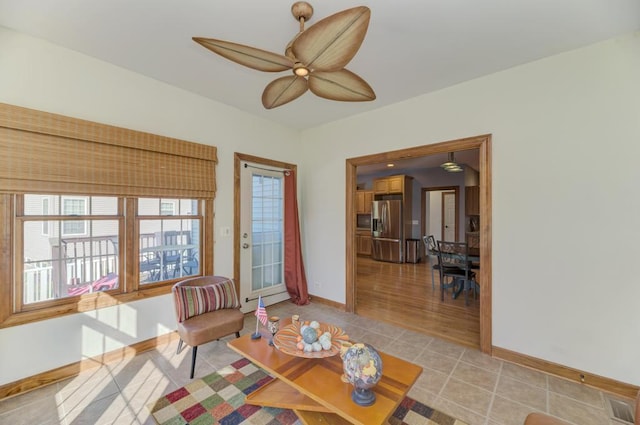 living room with a ceiling fan, light tile patterned flooring, and baseboards