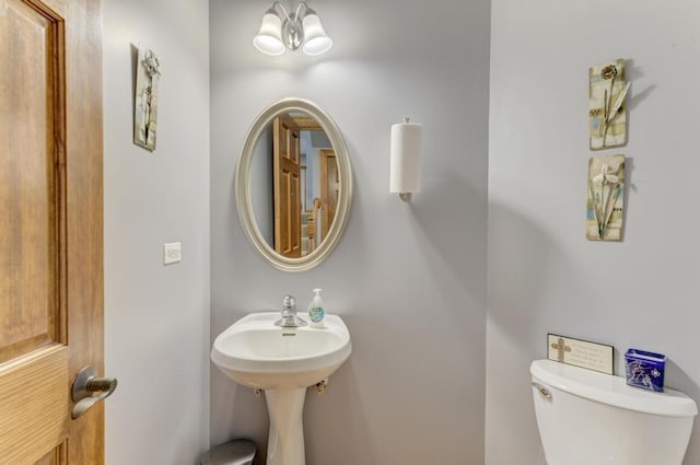 half bathroom with toilet and a notable chandelier