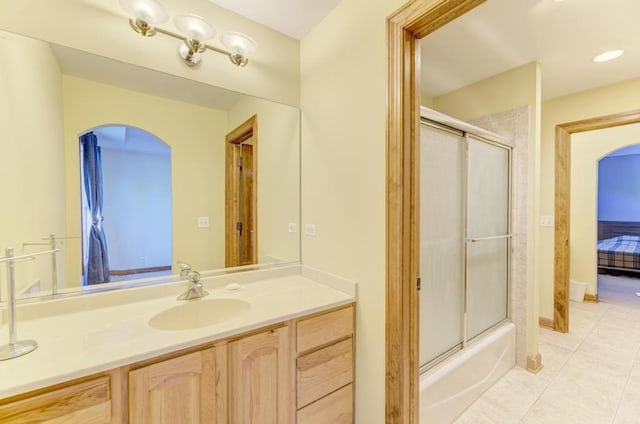 ensuite bathroom with ensuite bathroom, bath / shower combo with glass door, tile patterned flooring, and vanity