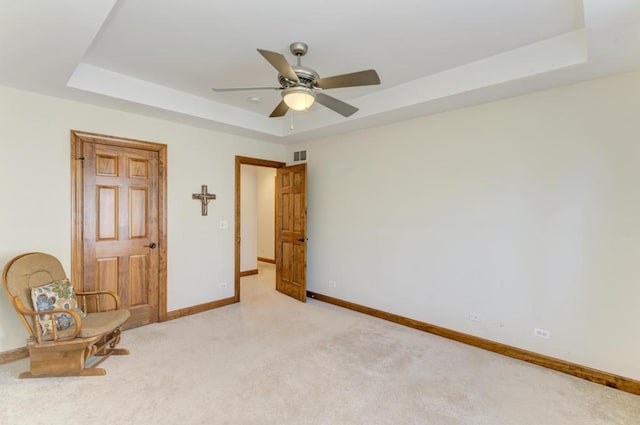 unfurnished room with light carpet, baseboards, and a raised ceiling