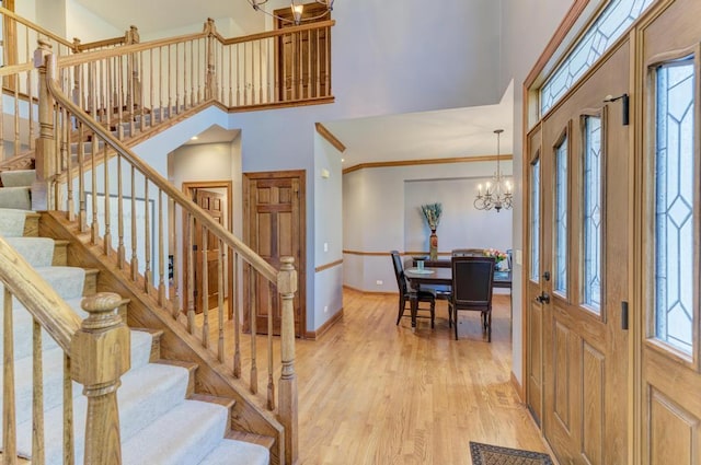 entryway featuring light wood-style floors, plenty of natural light, a high ceiling, and an inviting chandelier