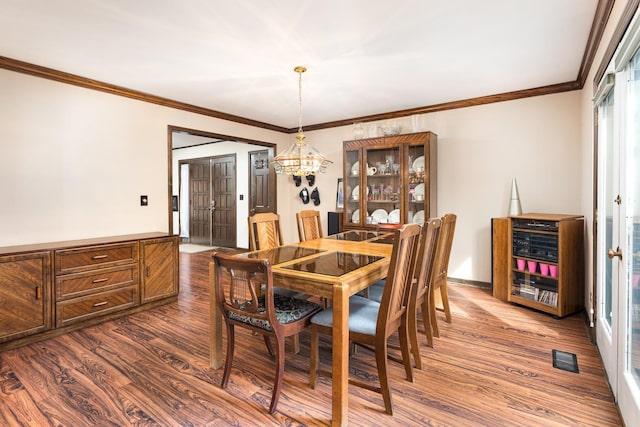 dining room with visible vents, baseboards, dark wood finished floors, and crown molding