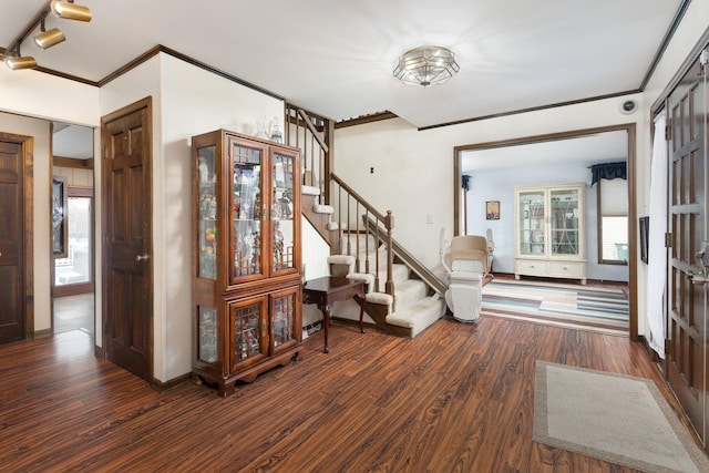 foyer featuring track lighting, wood finished floors, stairway, crown molding, and baseboards