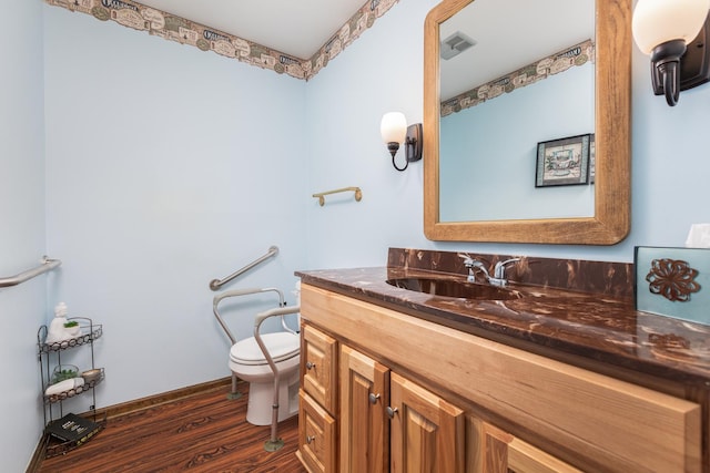 bathroom with vanity, wood finished floors, visible vents, baseboards, and toilet