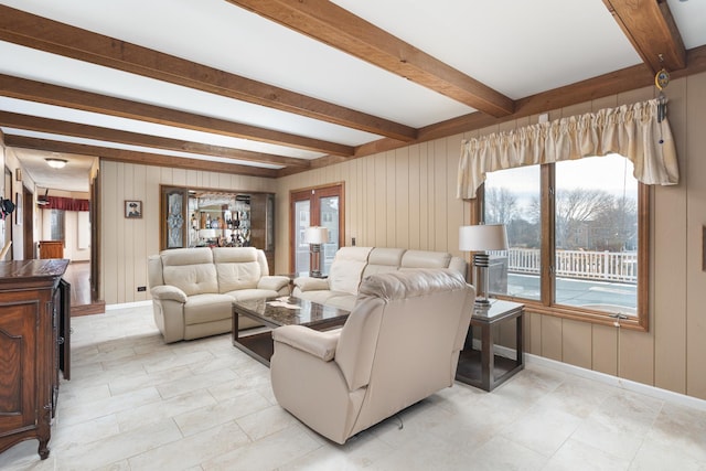 living area featuring beamed ceiling, baseboards, and wooden walls