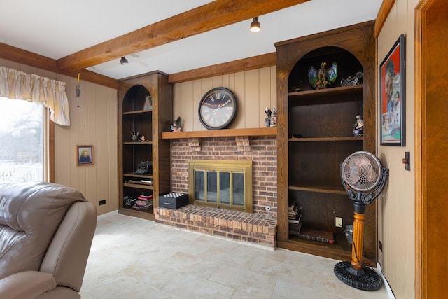 living area with beamed ceiling, built in shelves, wood walls, and a fireplace