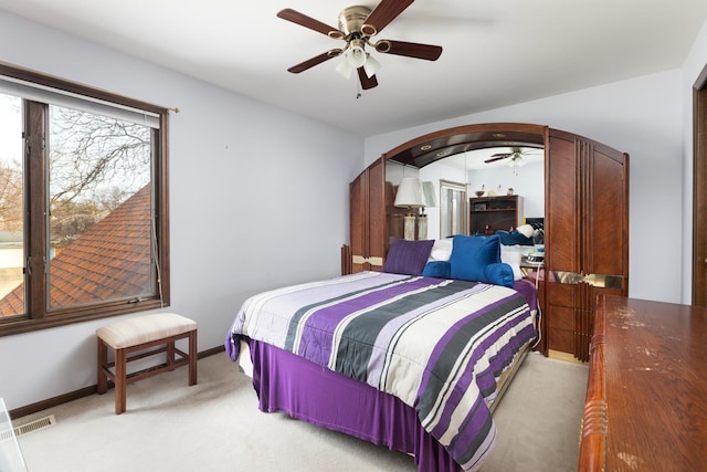 bedroom featuring visible vents, baseboards, light carpet, arched walkways, and a ceiling fan