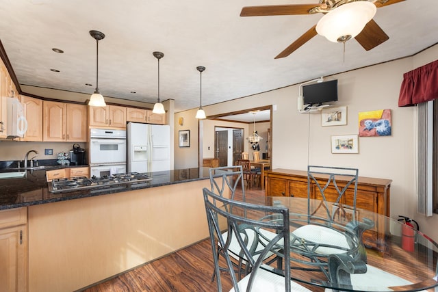 kitchen with white appliances, light brown cabinets, a peninsula, a sink, and dark wood-type flooring