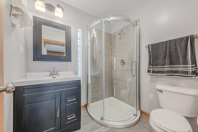 bathroom featuring toilet, a shower with door, and vanity