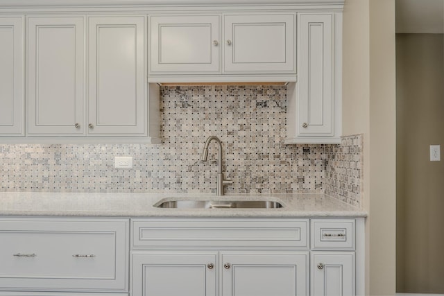 kitchen with sink, white cabinets, tasteful backsplash, and light stone countertops