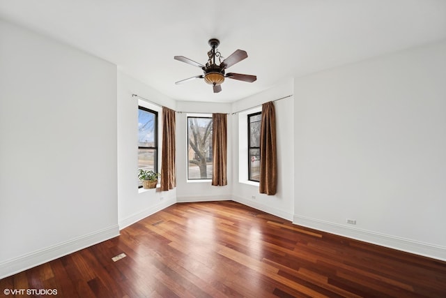 empty room with ceiling fan, baseboards, and wood finished floors