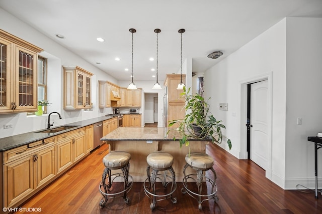 kitchen with glass insert cabinets, decorative light fixtures, a center island, stainless steel appliances, and a sink