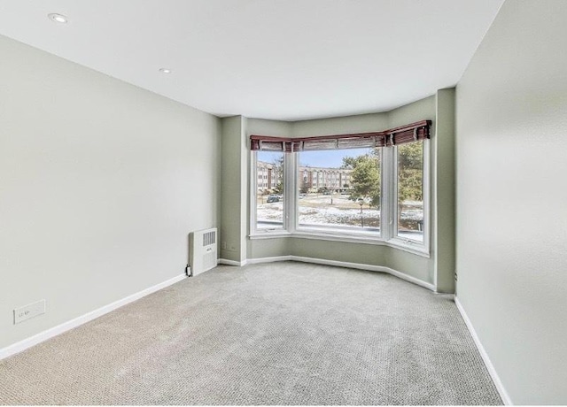 empty room featuring radiator heating unit, baseboards, and carpet flooring